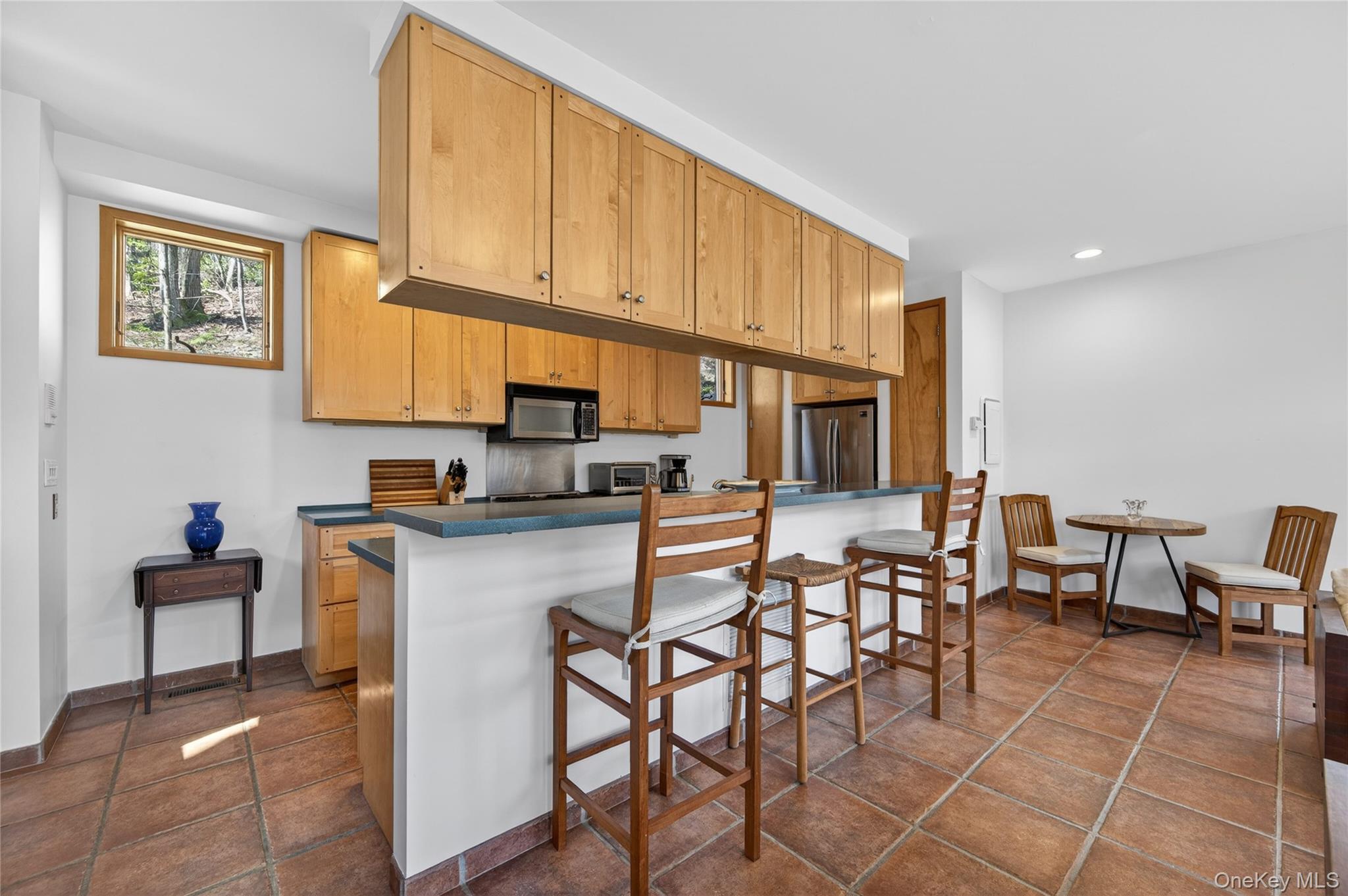 428 Harbor Road, Unit C Syosset, NY 11791 - Photo 13 of 29 Kitchen featuring light wood cabinetry, stainless steel appliances, dark countertops, and terra cotta tile flooring