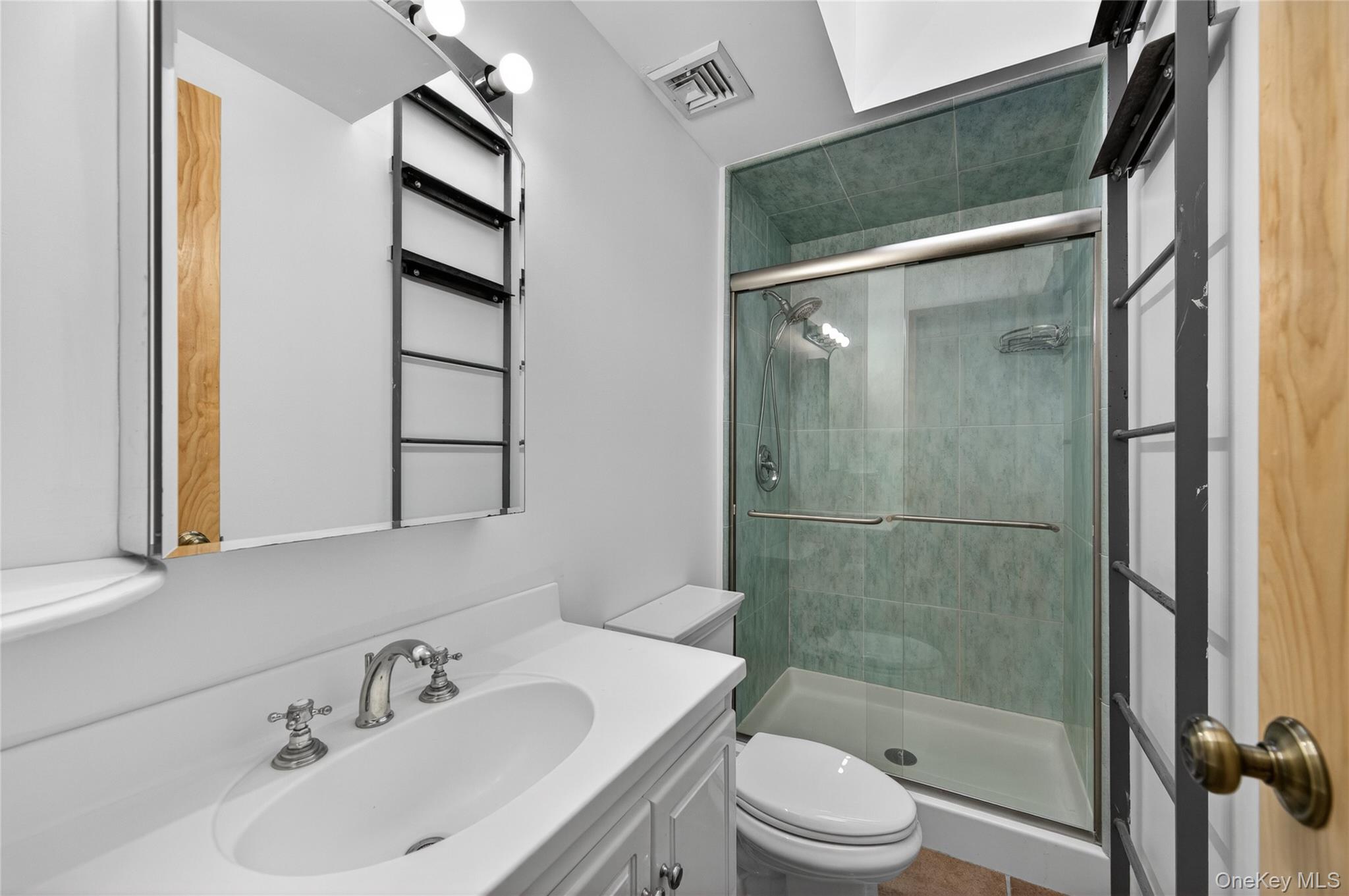 428 Harbor Road, Unit C Syosset, NY 11791 - Photo 25 of 29 Bathroom featuring a white vanity with an integrated sink, polished chrome faucet, and mirrored medicine cabinet with exposed shelving