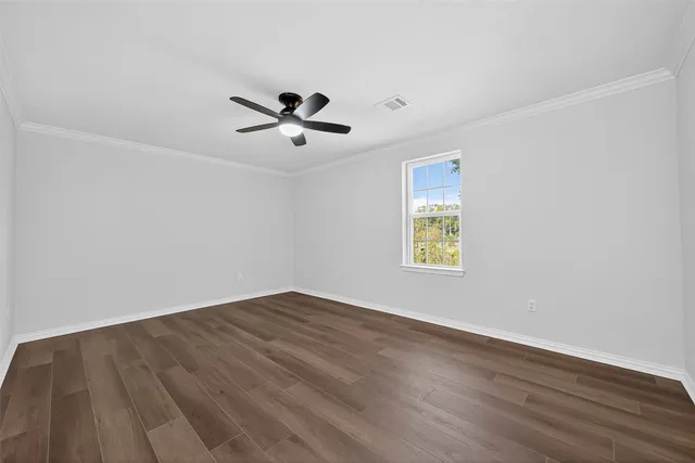 an empty room with wooden floor ceiling fan and windows