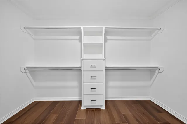 an empty room with wooden floor closet and windows