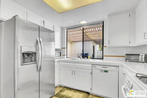 a kitchen with white cabinets and window