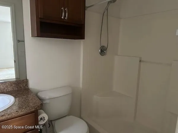 a bathroom with a granite countertop toilet and a sink