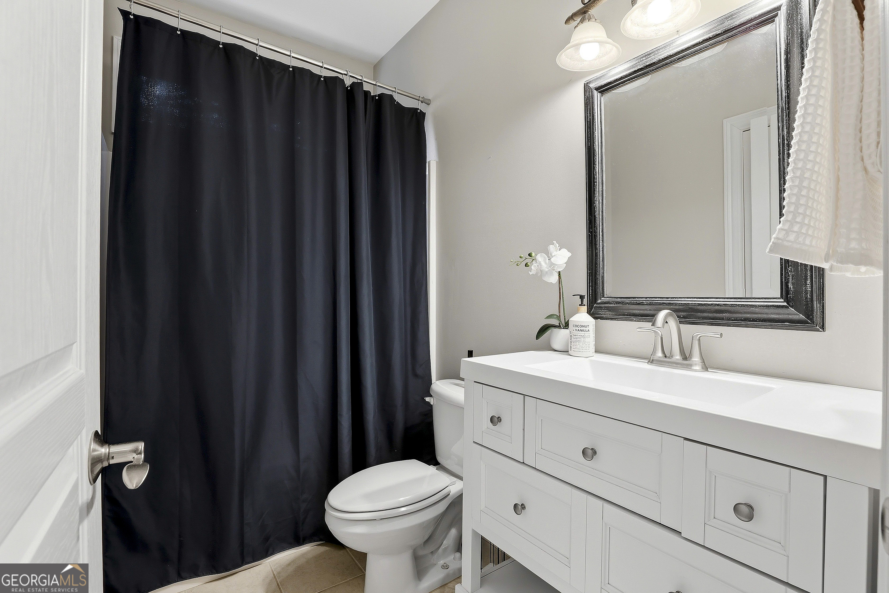 108 Tullamore Trail Tyrone, GA 30290 - Photo 32 of 54 a bathroom with a sink a toilet a mirror and shower curtain
