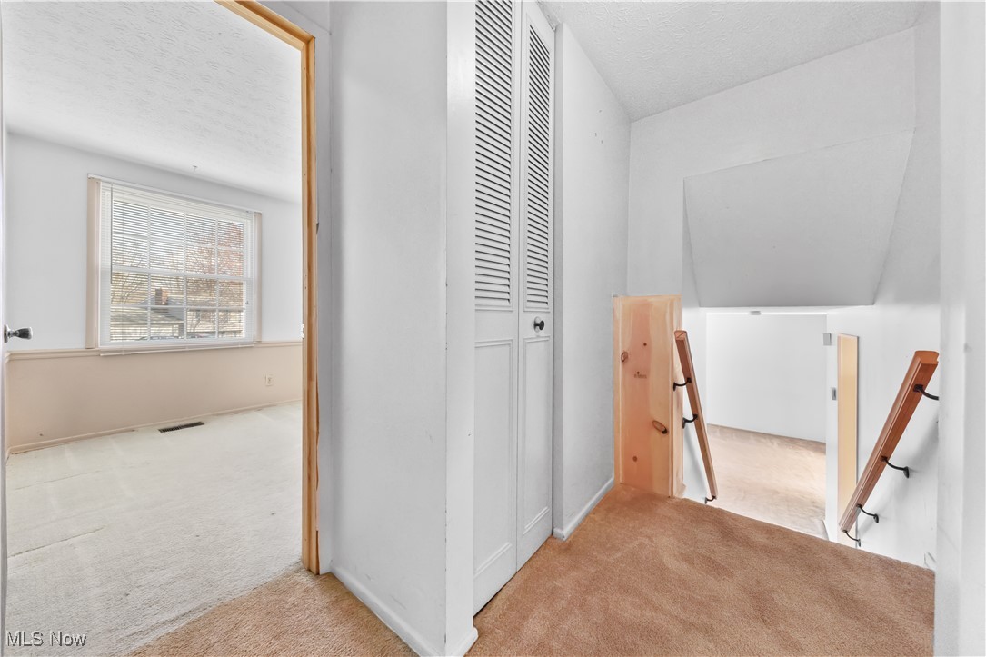 4301 Baird Road Stow, OH 44224 - Photo 23 of 50 Hallway featuring a textured ceiling, visible vents, carpet floors, and an upstairs landing