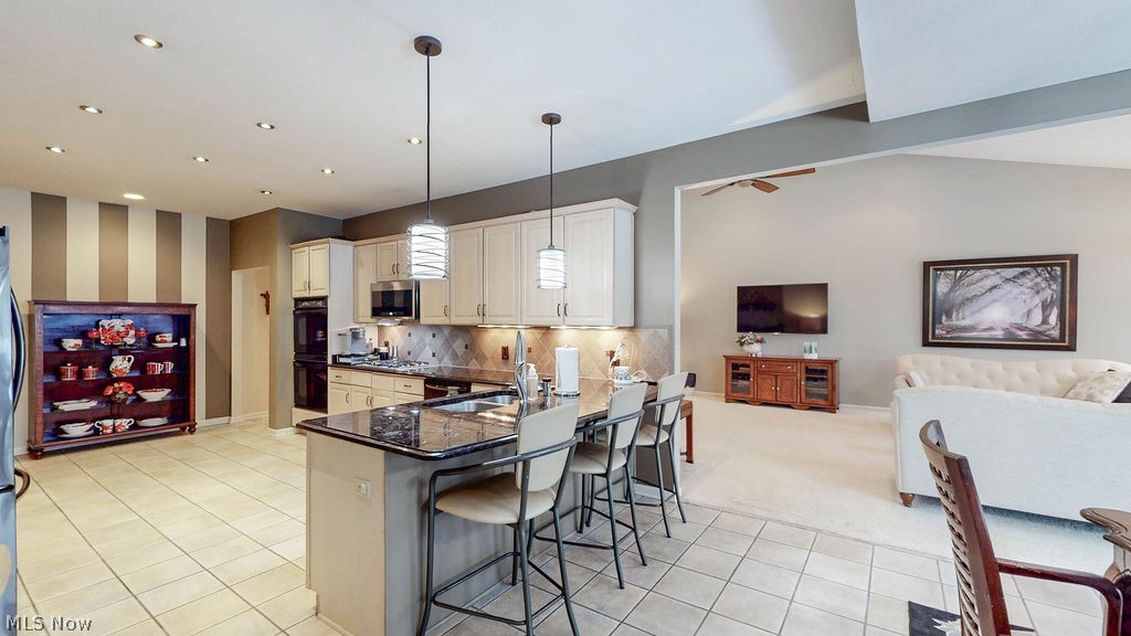 36845 Aberdeen Lane Solon, OH 44139 - Photo 24 of 24 Kitchen featuring open floor plan, a kitchen breakfast bar, wallpapered walls, hanging light fixtures, and dark stone countertops