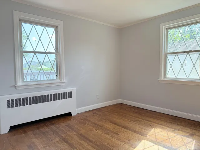 a view of an empty room with wooden floor and windows