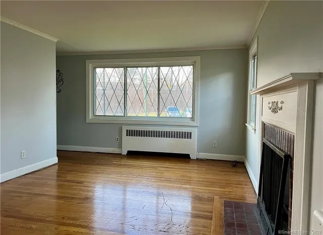 a view of an empty room with a window and wooden floor