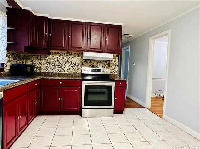 a kitchen with granite countertop a stove top oven and cabinets