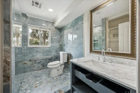 a bathroom with a granite countertop sink a toilet a mirror and shower