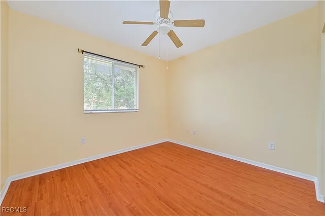 an empty room with a window and a fan