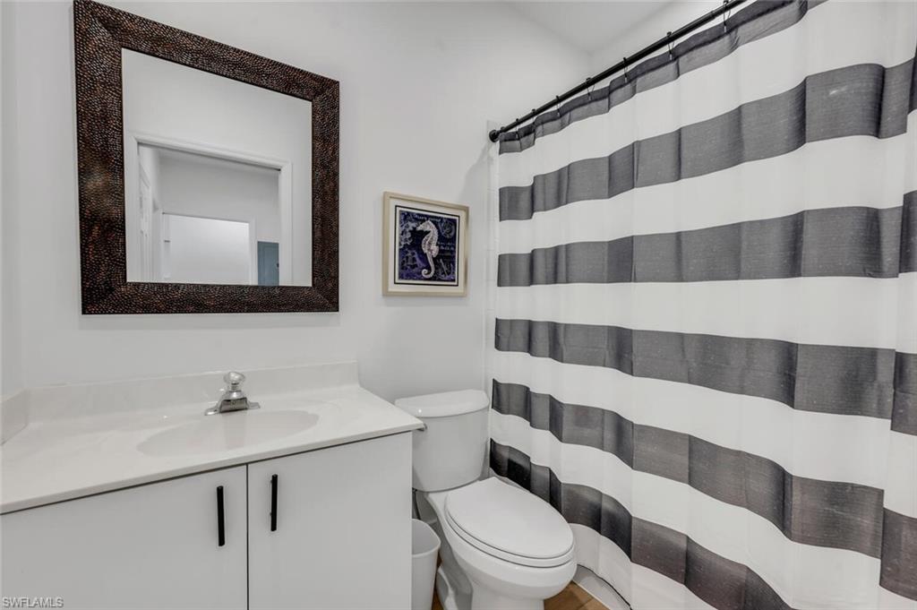 6010 Chardonnay Lane, Unit 304 Naples, FL 34119 - Photo 13 of 29 a bathroom with a sink a toilet a mirror and shower curtain
