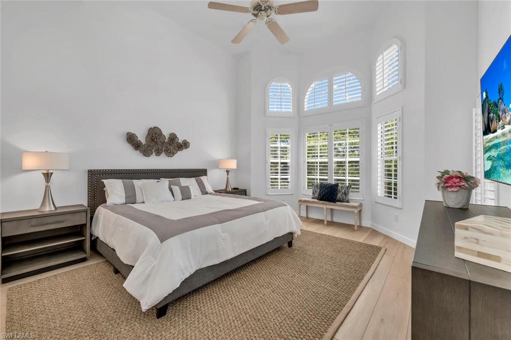 6010 Chardonnay Lane, Unit 304 Naples, FL 34119 - Photo 9 of 29 a bedroom with a bed and a chandelier