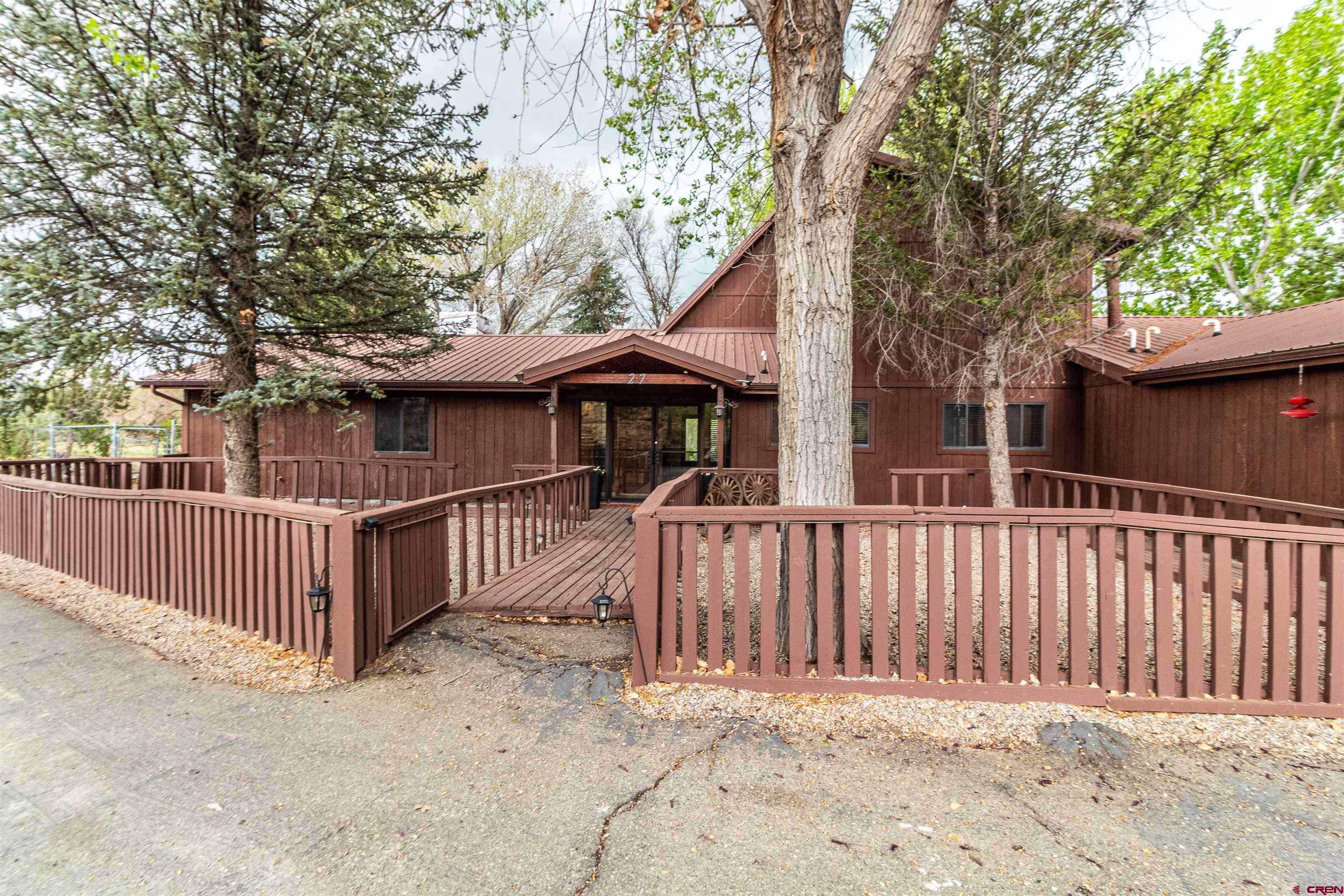 a view of a house with a small yard and a large tree