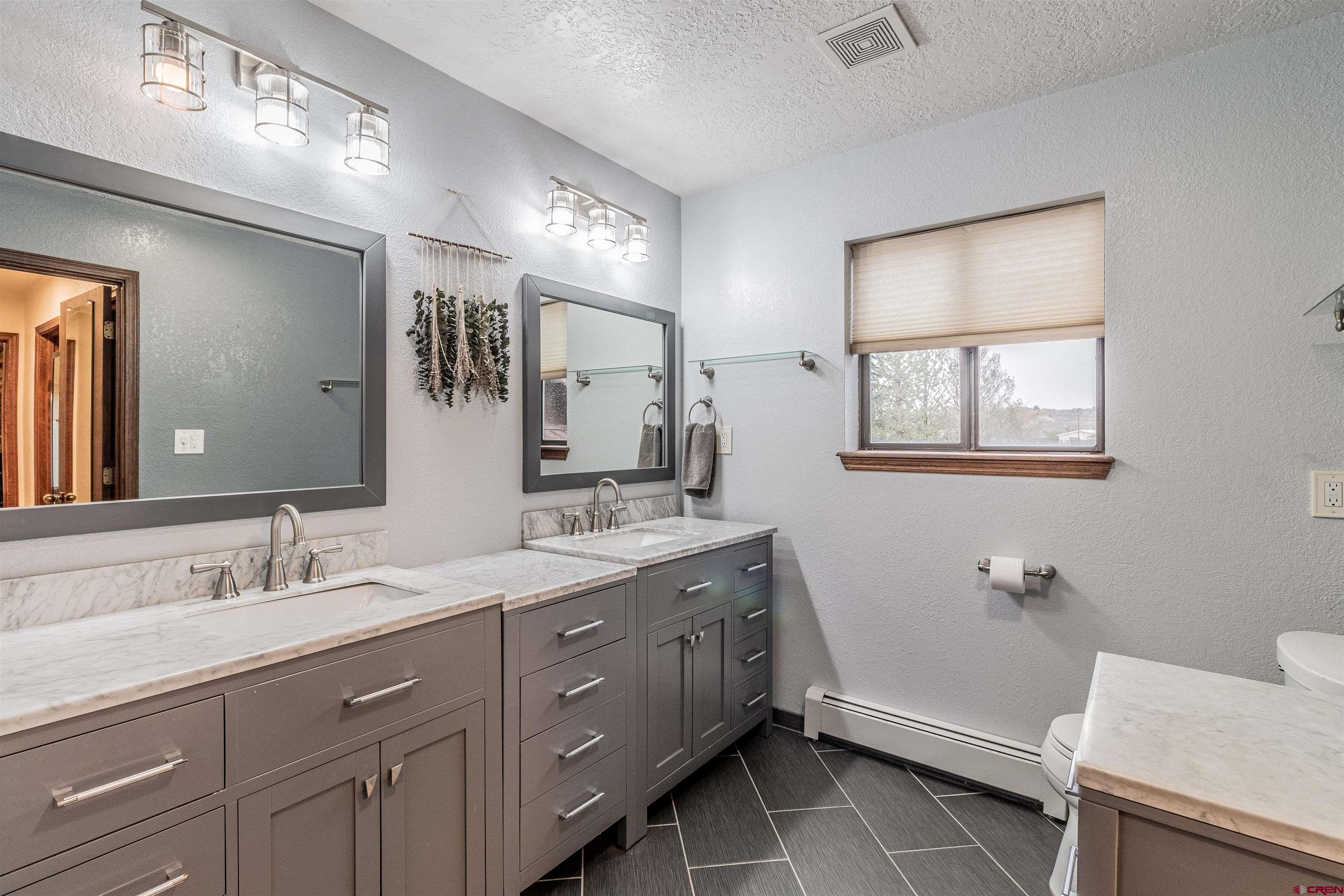 27 Road 3025 Aztec, NM 87410 - Photo 33 of 45 a bathroom with a double vanity sink a toilet and a mirror