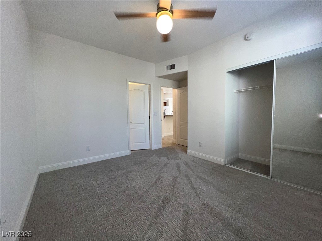 1705 King James Street, Unit 203 Las Vegas, NV 89144 - Photo 11 of 21 Unfurnished bedroom featuring dark colored carpet, a ceiling fan, and a closet