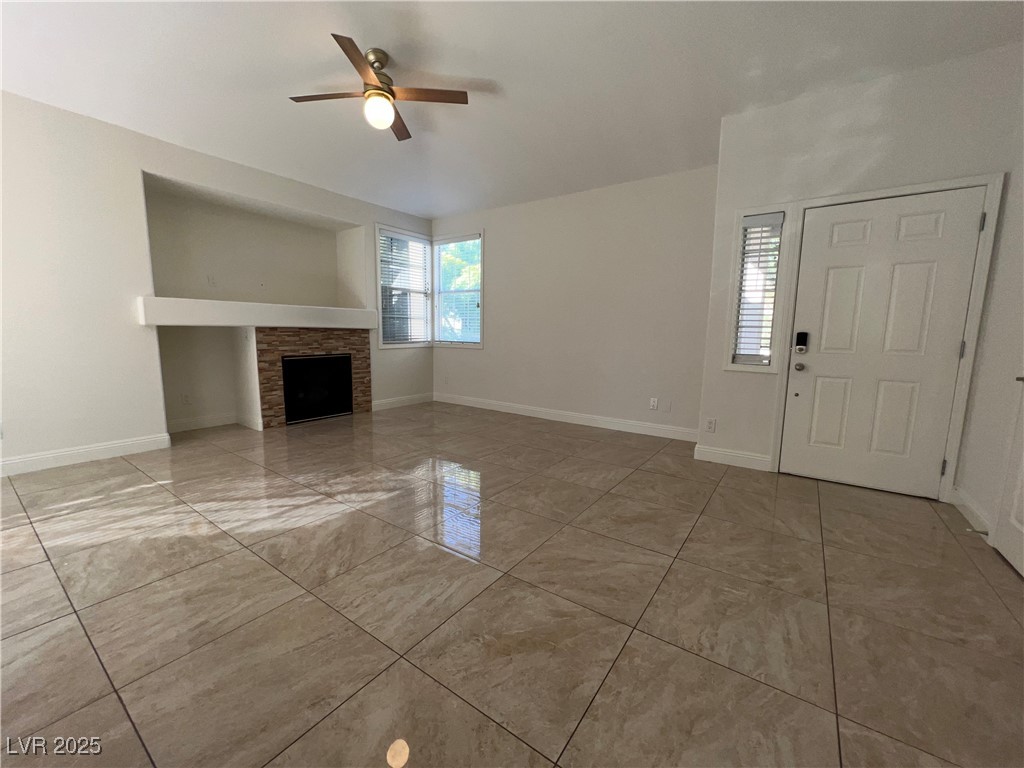1705 King James Street, Unit 203 Las Vegas, NV 89144 - Photo 3 of 21 Unfurnished living room featuring ceiling fan and a fireplace