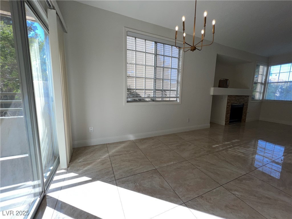 1705 King James Street, Unit 203 Las Vegas, NV 89144 - Photo 9 of 21 Unfurnished dining area featuring a chandelier, a fireplace, and light tile patterned floors