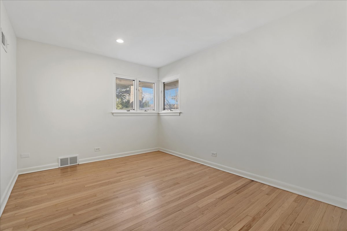 8314 Gross Point Road Morton Grove, IL 60053 - Photo 16 of 28 an empty room with wooden floor and windows