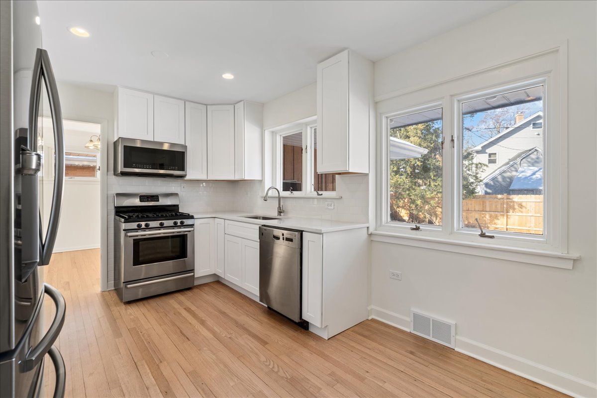 8314 Gross Point Road Morton Grove, IL 60053 - Photo 9 of 28 a kitchen with granite countertop a stove a sink and a refrigerator