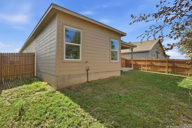a view of backyard of house with wooden fence