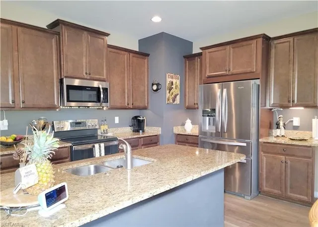 a kitchen with granite countertop a refrigerator a stove a sink a counter space and cabinets