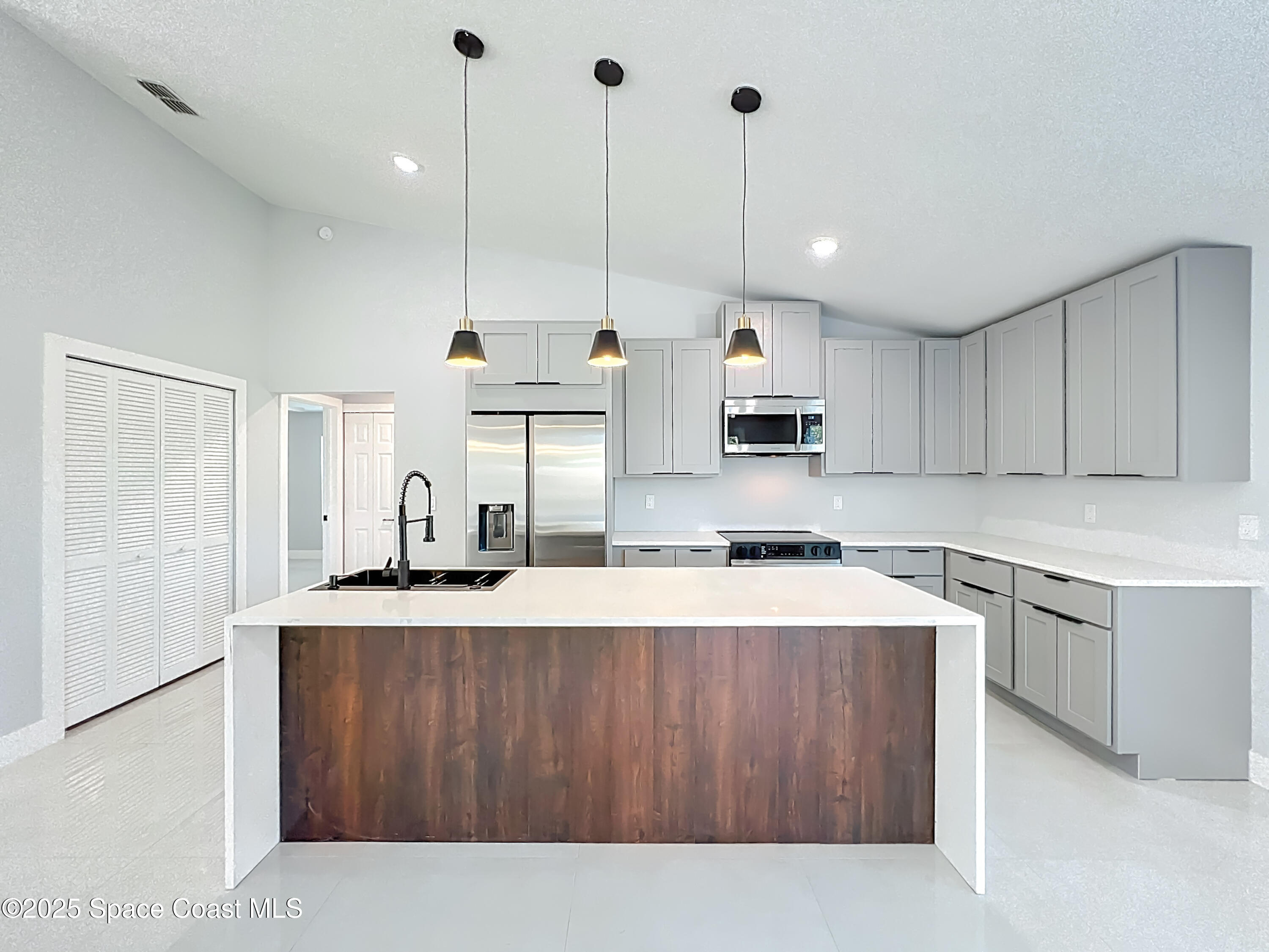 1911 Academy Street Northeast Palm Bay, FL 32905 - Photo 22 of 65 a kitchen with kitchen island a sink a stove a refrigerator and white cabinets
