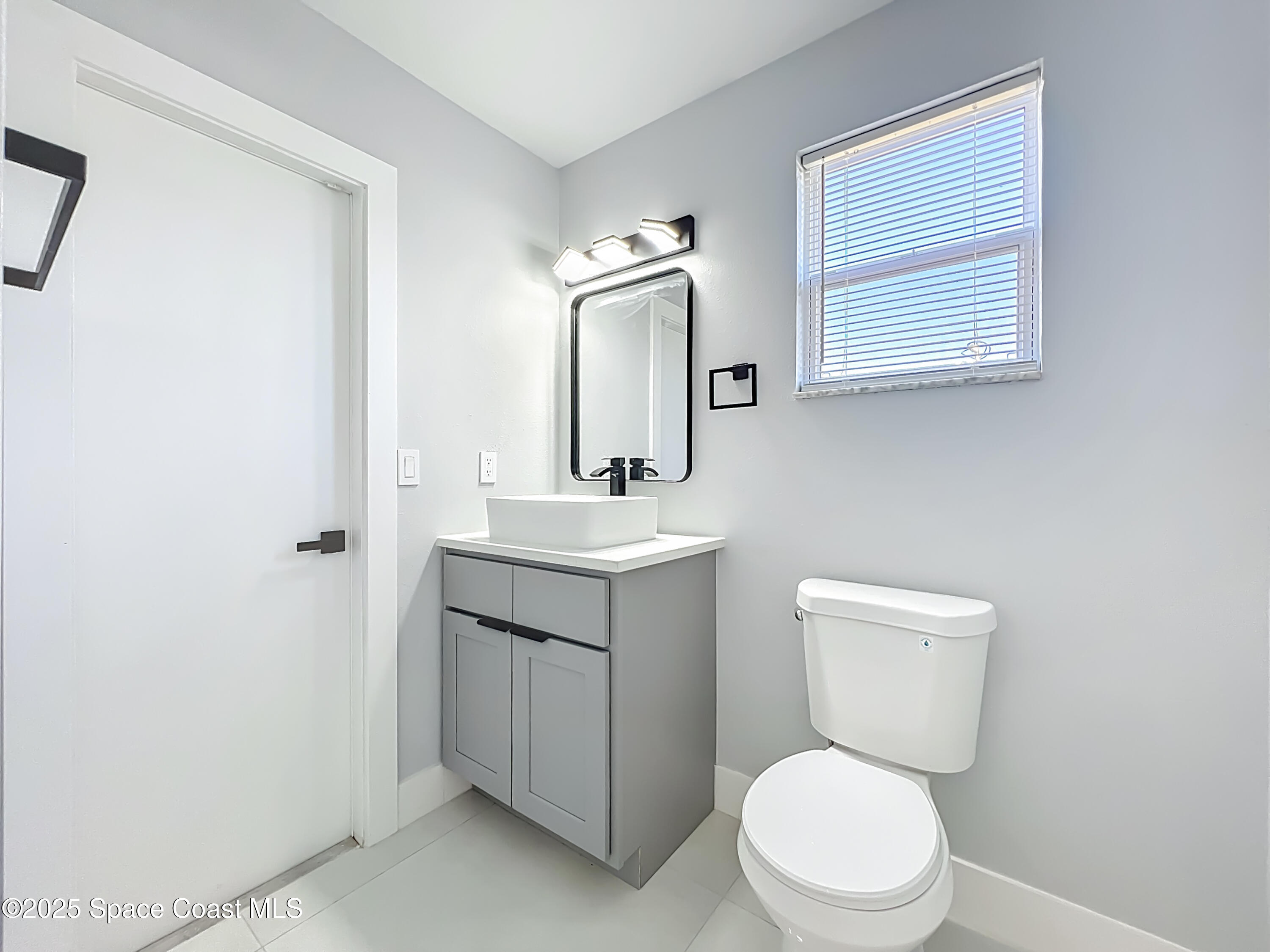 1911 Academy Street Northeast Palm Bay, FL 32905 - Photo 31 of 65 a bathroom with a toilet a sink a mirror and a window
