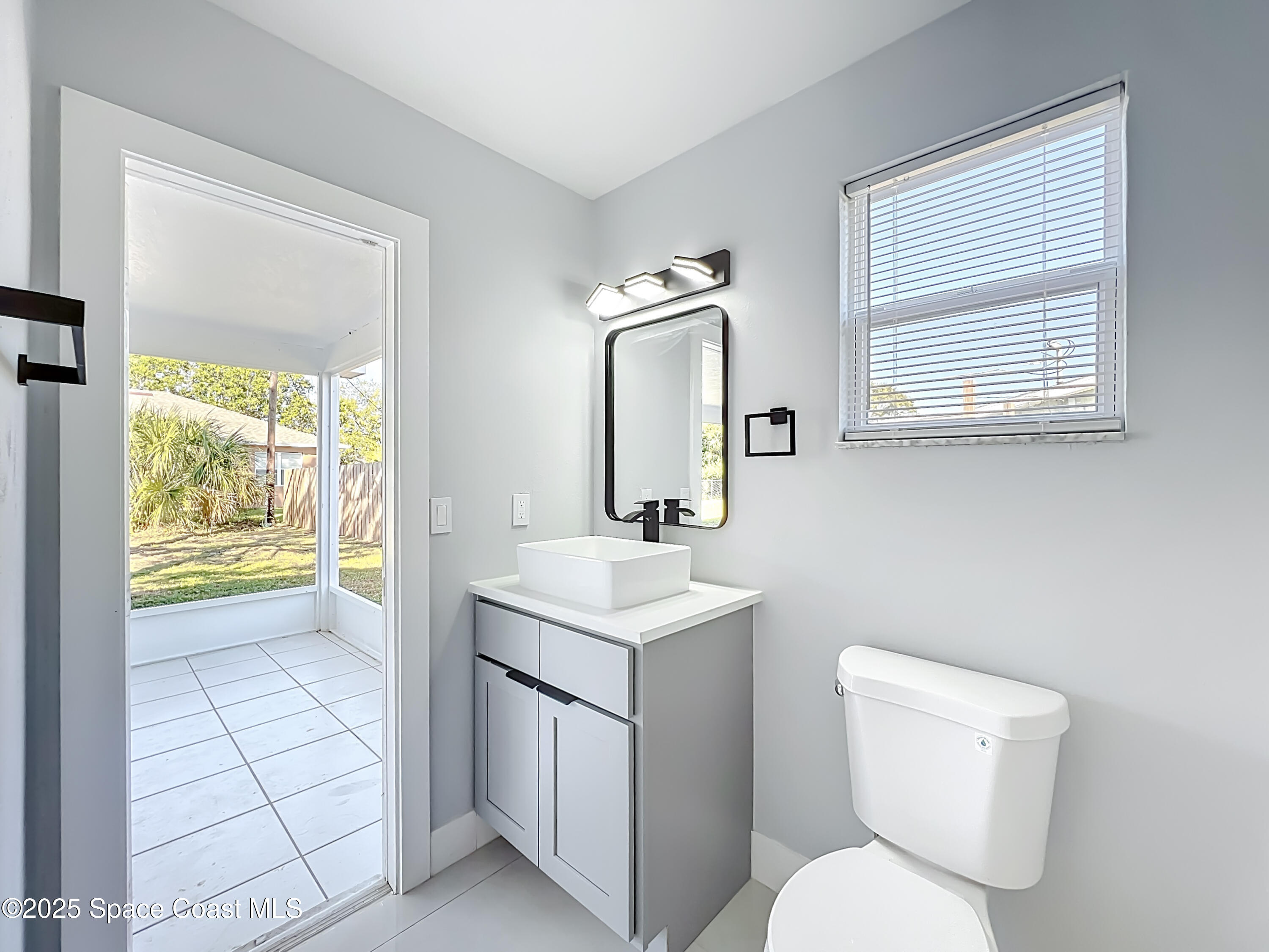 1911 Academy Street Northeast Palm Bay, FL 32905 - Photo 32 of 65 a bathroom with a toilet a sink a vanity and mirror