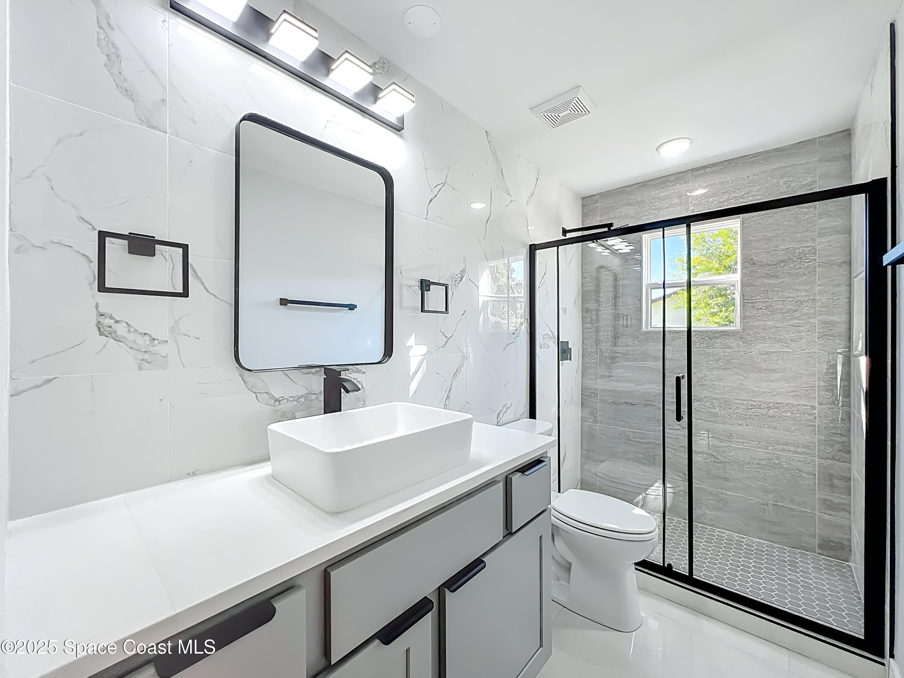 1911 Academy Street Northeast Palm Bay, FL 32905 - Photo 46 of 65 a bathroom with a sink a toilet a mirror and shower
