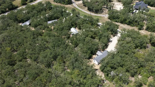 an aerial view of residential house with outdoor space and trees all around