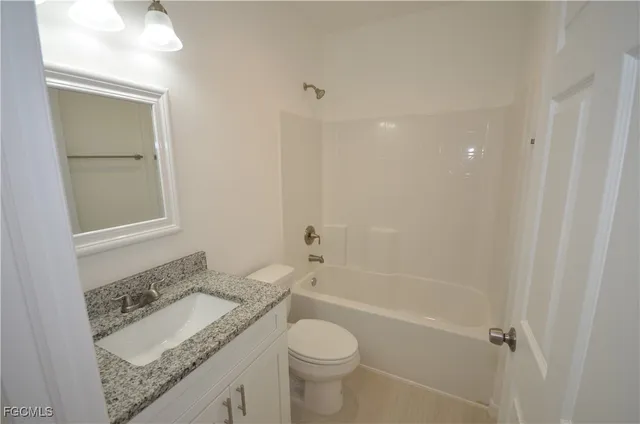 a bathroom with a granite countertop toilet a sink and a mirror