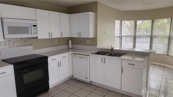 a kitchen with granite countertop white cabinets and black appliances