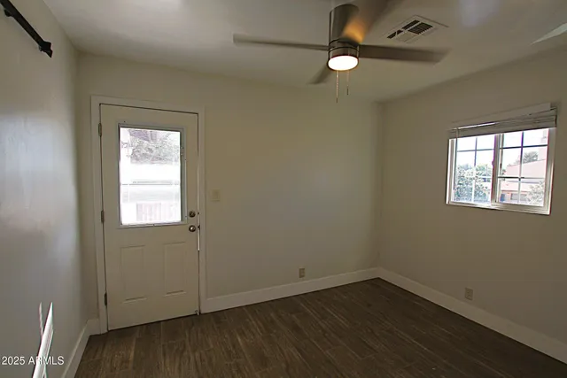 a view of empty room with wooden floor and fan