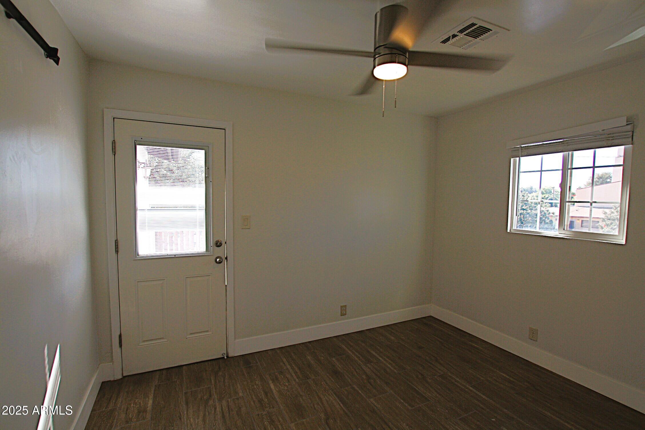 1333 East Flower Street, Unit REAR Phoenix, AZ 85014 - Photo 20 of 34 an empty room with wooden floor chandelier fan and windows