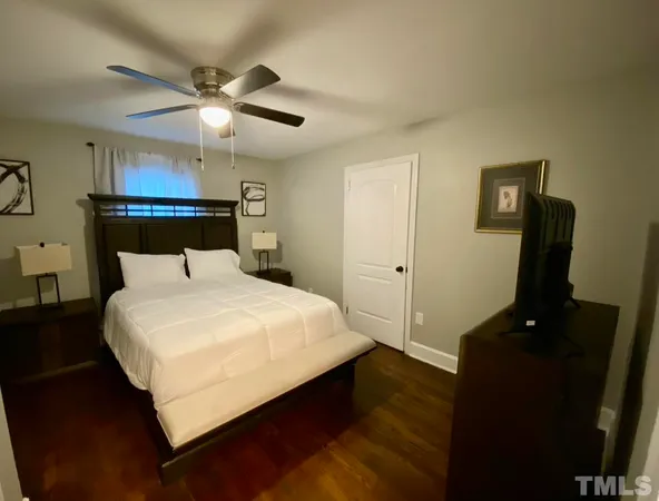 a bedroom with a bed and a flat tv screen on the dresser
