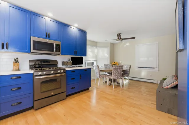 a kitchen with stainless steel appliances granite countertop a stove top oven a sink dishwasher a dining table and chairs with wooden floor