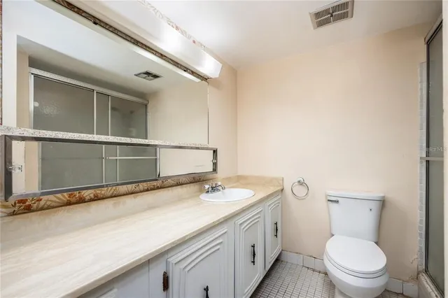 a bathroom with a granite countertop toilet sink and mirror