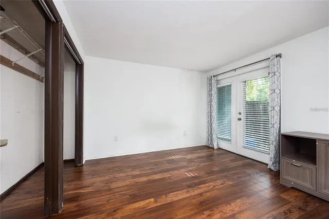an empty room with wooden floor fireplace and windows