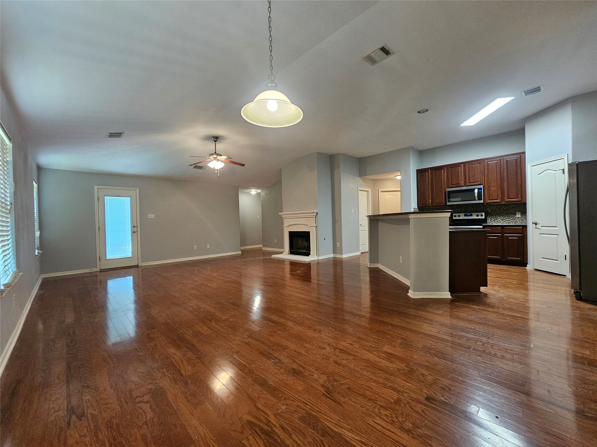 2035 Intrepid Drive Buda, TX 78610 - Photo 5 of 26 Rich hardwood flooring flows through this adaptable open-concept living space with a focal fireplace.