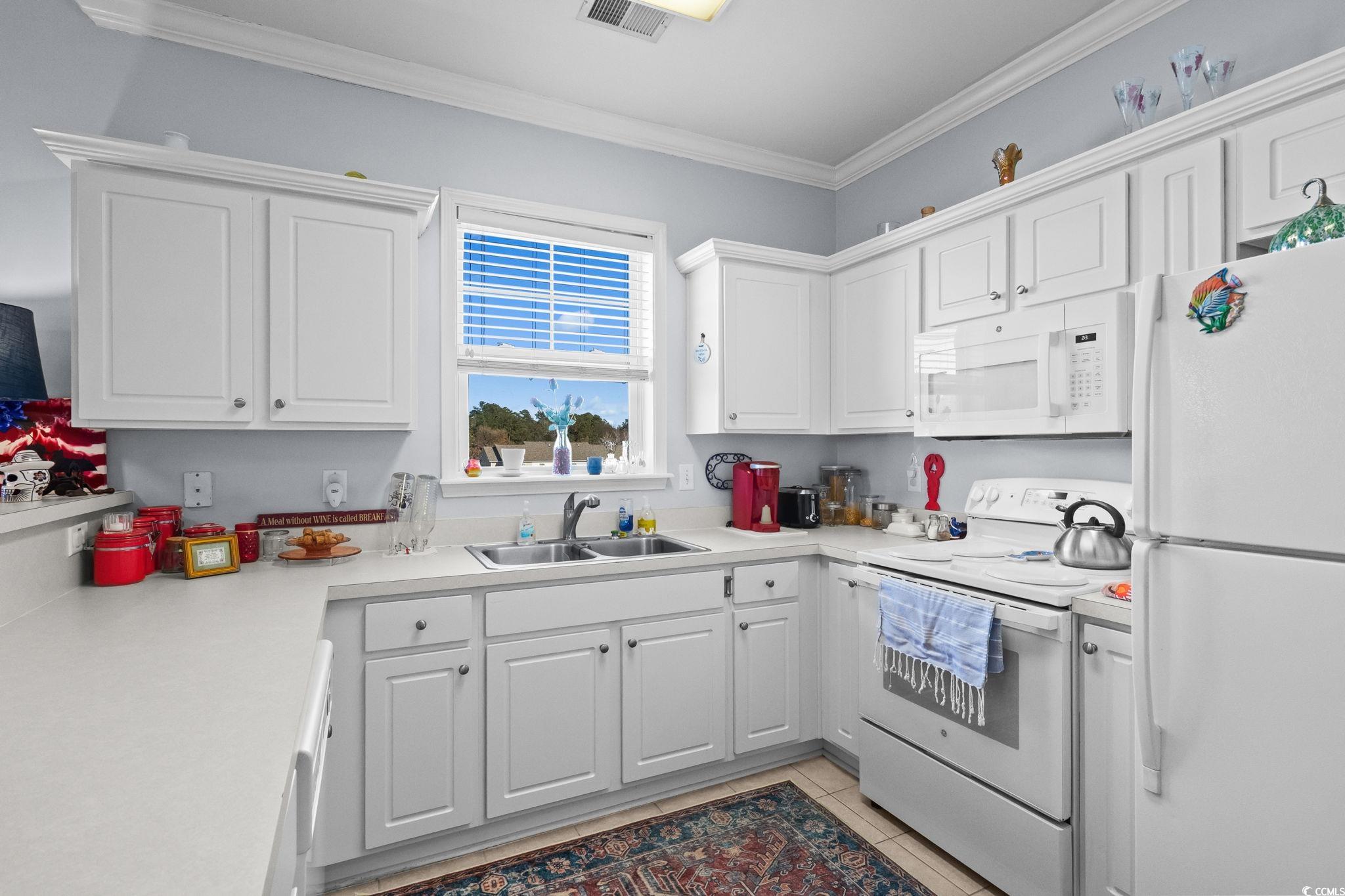 336 Kiskadee Loop, Unit 19O Conway, SC 29526 - Photo 11 of 26 Kitchen featuring white appliances, white cabinetry, light countertops, crown molding, and light tile patterned floors