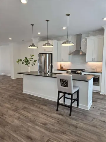 a kitchen with stainless steel appliances granite countertop a stove a sink and a wooden floors