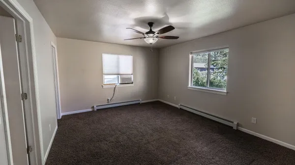 an empty room with a window and a fan