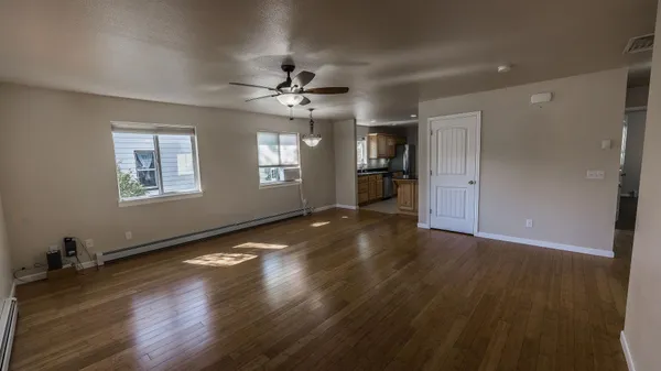 a view of an empty room with a window and wooden floor
