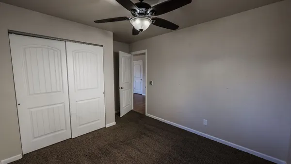 an empty room with closet and a chandelier fan