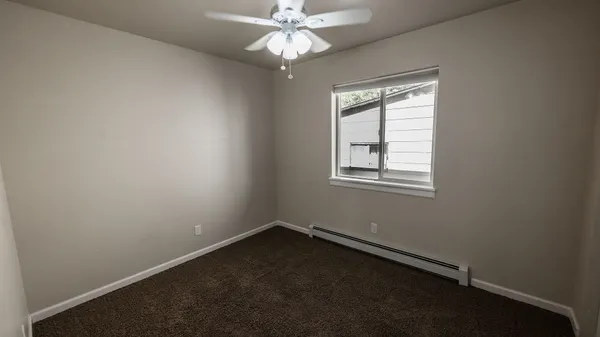 an empty room with a window and a fan