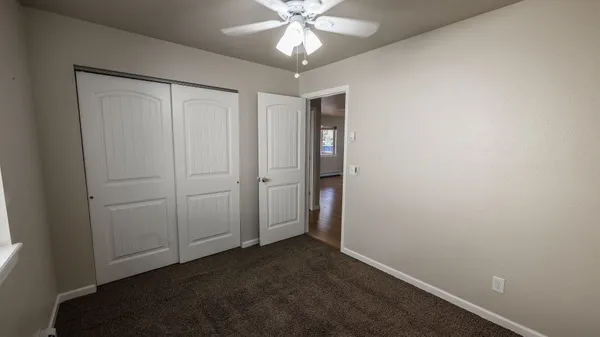 an empty room with a chandelier fan and closet