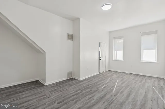 an empty room with wooden floor and windows