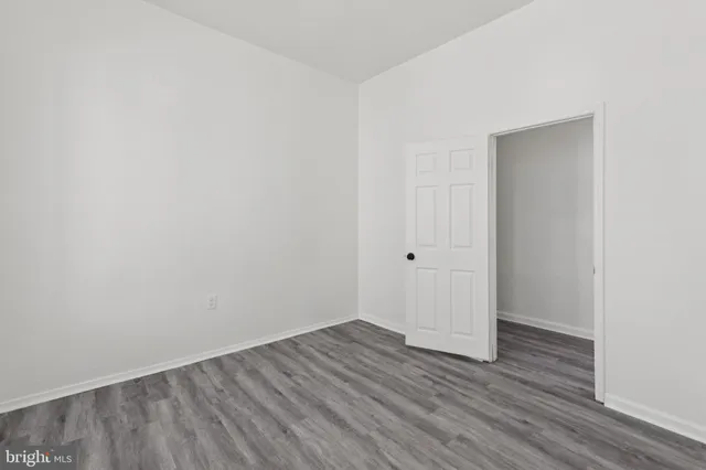 an empty room with wooden floor & closet area
