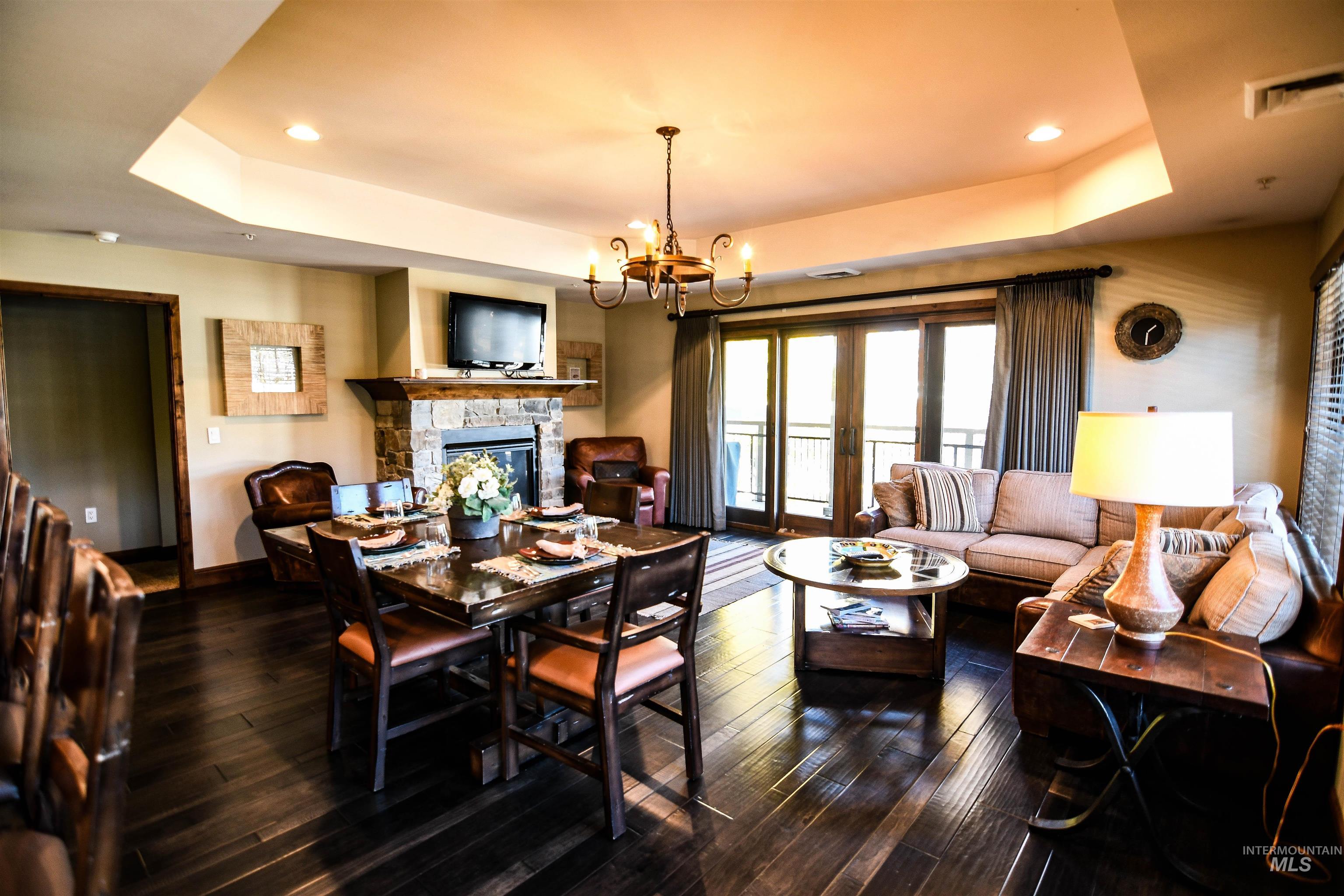 616 North 3rd Street, Unit 215 McCall, ID 83638 - Photo 8 of 36 Dining space with a raised ceiling, a stone fireplace, a chandelier, dark wood-style floors, and recessed lighting