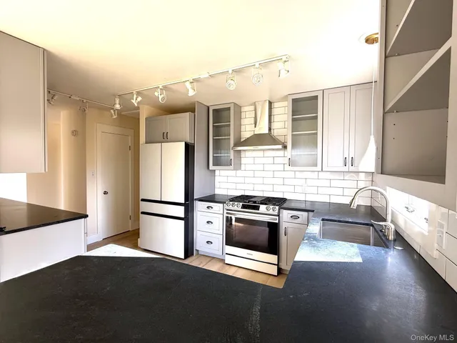 a kitchen with granite countertop a refrigerator and a stove top oven